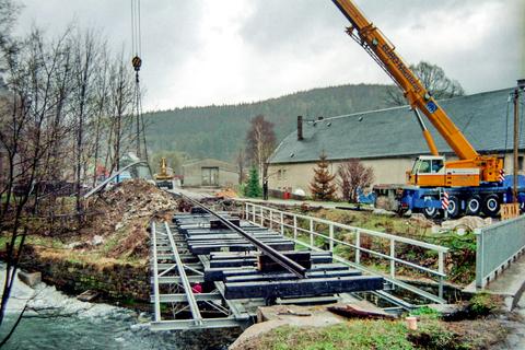 Mit dem Kran werden auch gleich die Schienen auf den eingebauten Brückenüberbau gehoben.