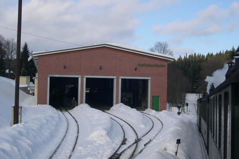 Blick zur Fahrzeughalle mit Schneebergen zwischen den Gleisen.