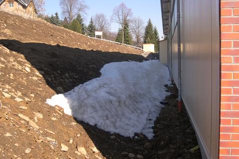 Entlang der hangseitigen Wand der Fahrzeughalle halten sich noch immer größere Schneereste.