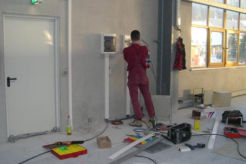 Installation der Sicherungs- und Schaltkästen der Niederspannungstrafos an der Hallenwand durch den Elektriker.