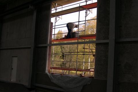 Blick durch die Fensteröffnung der Fahrzeughalle auf die Arbeiten am Klinkermauerwerk.