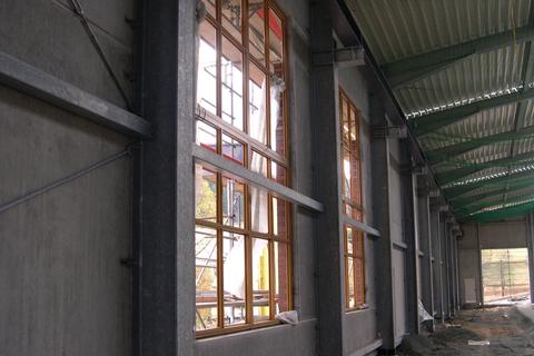 Eingesetzte Fensterrahmen in den ersten beiden Fensteröffnungen entlang der Front der Fahrzeughalle.
