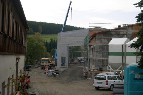 Blick von der Einfahrt an der Schlösselstraße auf die Baustelle mit dem Kran, der die Montage der Wandelemente unterstützt.