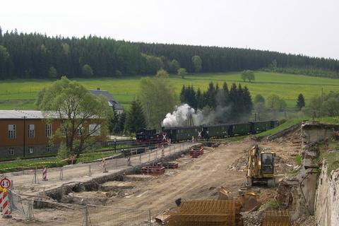 Der Personenzug der Museumsbahn passiert den Bahnübergang an der Baustelle.