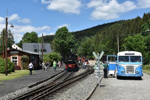 Übergang der Reisenden vom Dampfzug zum historischen Bus.