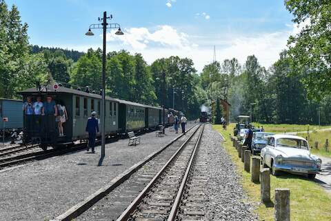 Während die Lok am Wasserhaus befüllt wird, steht der Wagenzug am Bahnsteig.