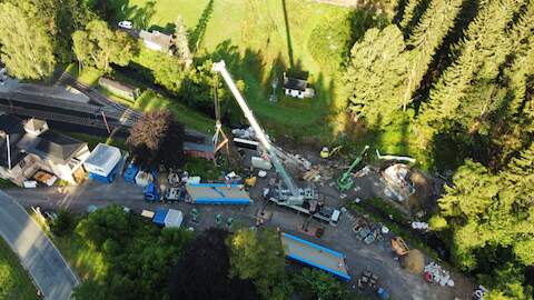 Die drei großen Teile der Stahlbrücke werden angeliefert und auf dem Aufstellplatz für die Endmontage positioniert.