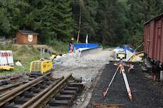 Mit Bagger und Radlader wird sukzessive Schotter in die Stahlwanne der Brücke eingebracht.