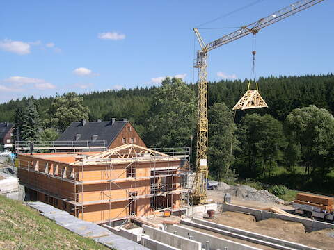 Die Dachbinder werden auf das Mehrzweckgebäude gehoben.